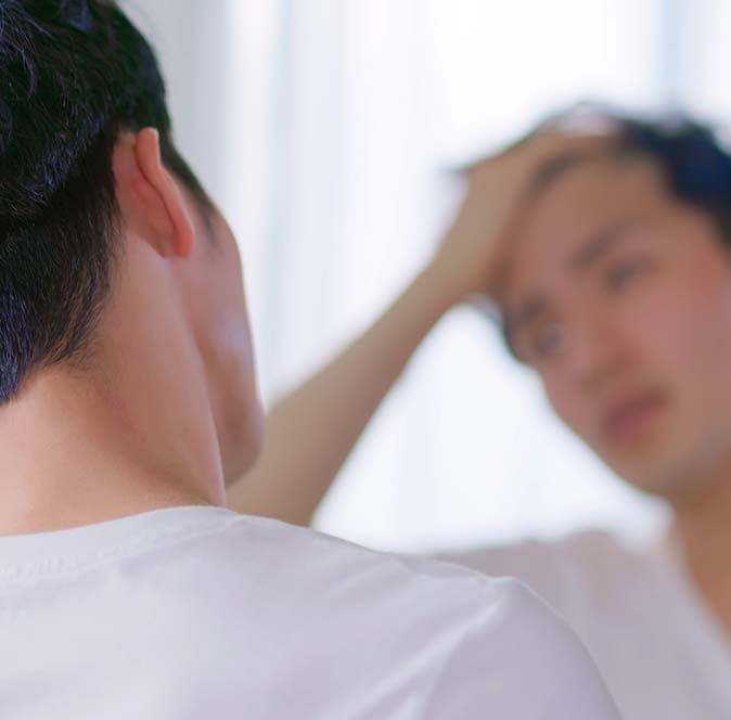 Man looking in the mirror at the growth of his hair