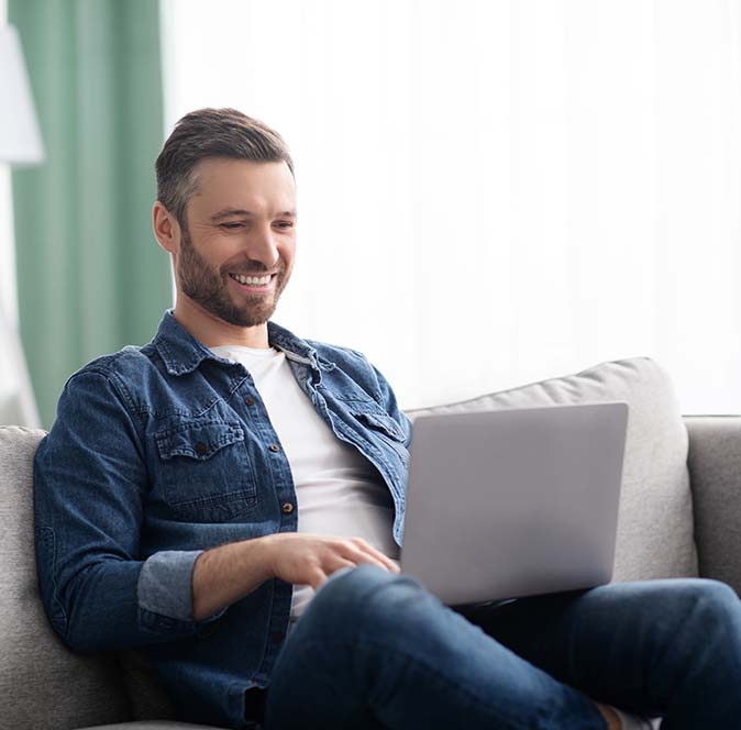 Middle age man sitting on the couch happily working