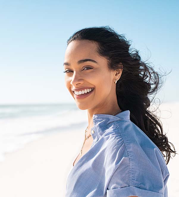 Woman smiling at the beach with the sun and wind to her face