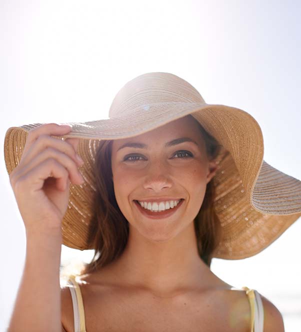 Woman in a hat with the sun to her back showing the results of dermaplaning