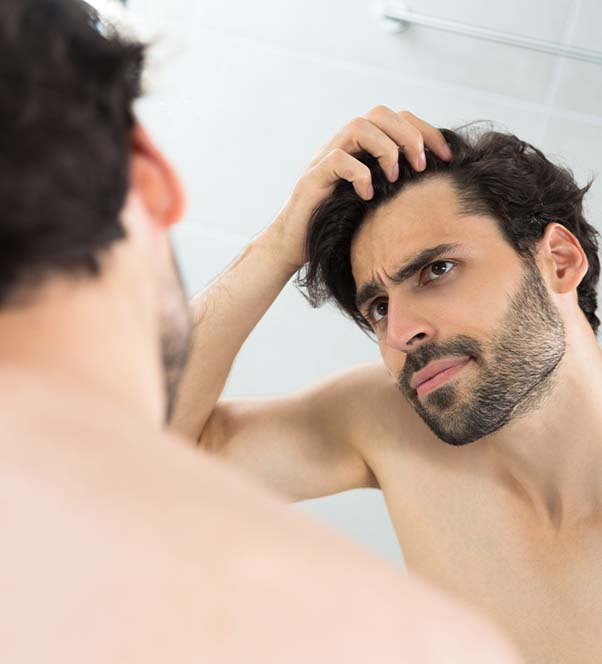 Man examining his hair loss in the mirror
