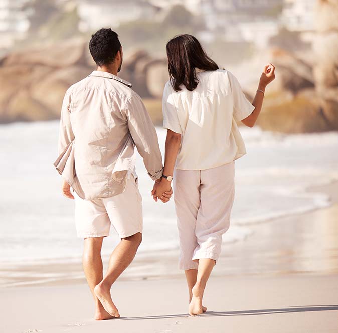 A couple holding hands and walking romantically along the beach