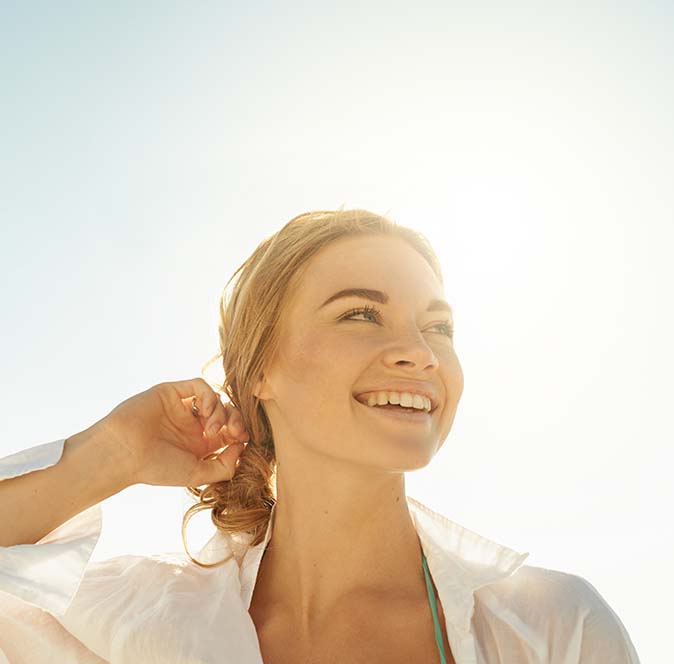 Woman with a big smile and the sun behind her